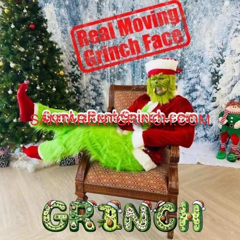 Grinch in a red Santa suit lounging in an armchair beside a decorated Christmas tree